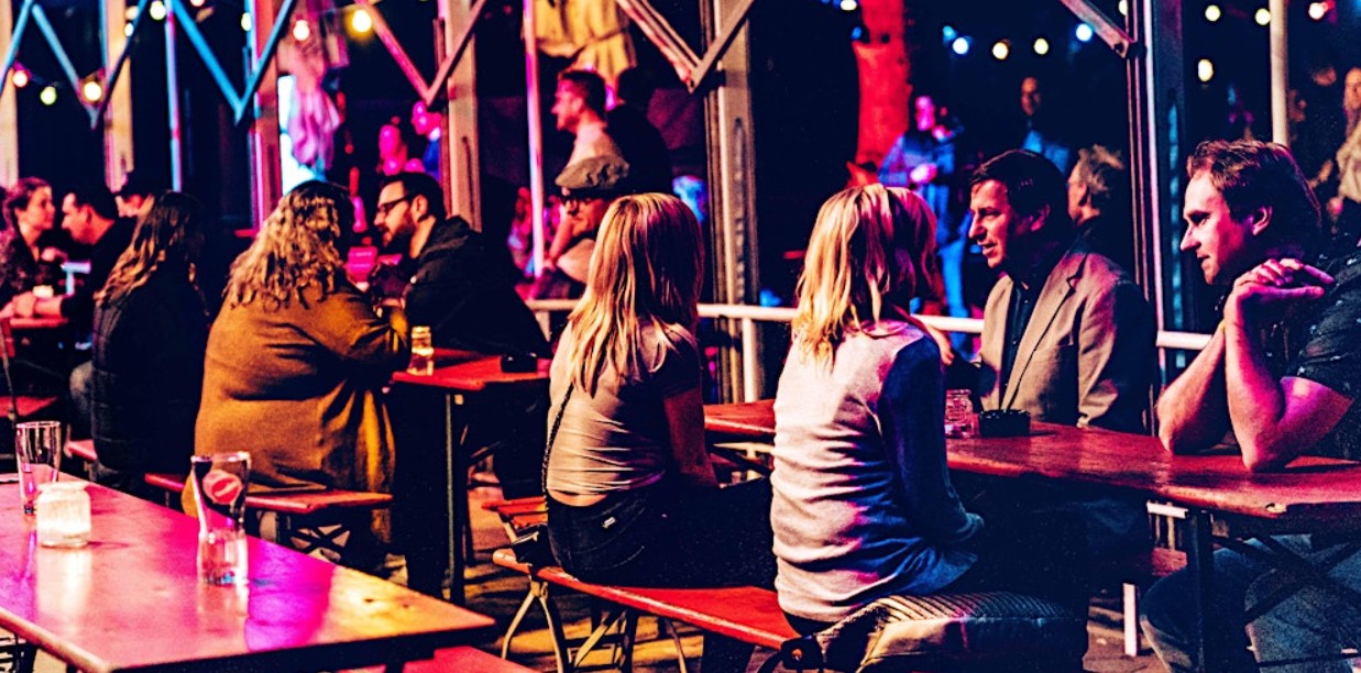 Singles im Gespräch an langen Tischen in einer Bar