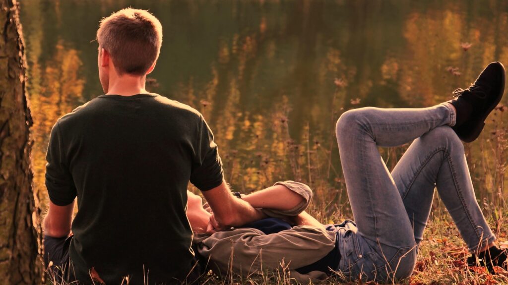 Paar sitzt im Abendlicht auf einer Wiese